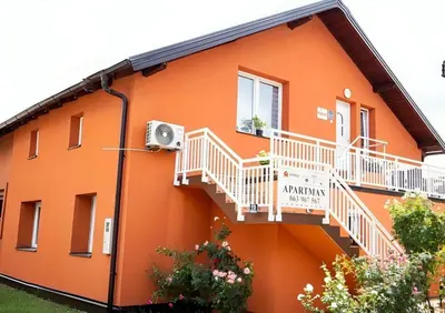 an orange building with white railings and a balcony at Sanlej Apartman