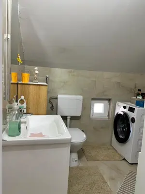 a bathroom with a toilet and a washing machine at Sanlej Apartman