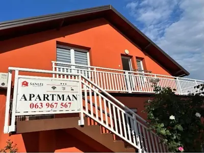 an orange building with a sign in front of it at Sanlej Apartman