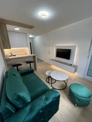 a living room with a green couch and a table at Lux Iva apartman in Doboj