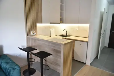 a small kitchen with a sink and two stools at Lux Iva apartman in Doboj