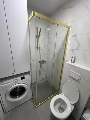 a bathroom with a washing machine and a toilet at Lux Iva apartman in Doboj