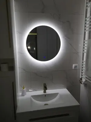 a bathroom with a sink and a round mirror at Lux Iva apartman in Doboj