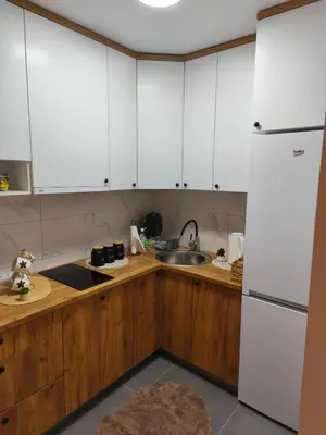 a kitchen with white cabinets and a sink and a refrigerator at Diva apartman, Doboj in Doboj