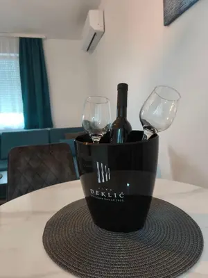 a bottle of wine and two wine glasses on a table at Diva apartman, Doboj in Doboj