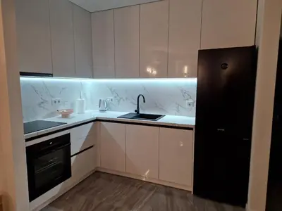 a kitchen with white cabinets and a sink and a black refrigerator at Apartman Bistrica in Livno