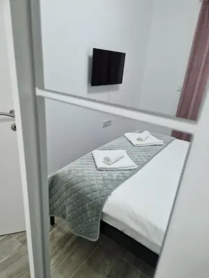 a small bed in a room with a mirror at Apartman Bistrica in Livno