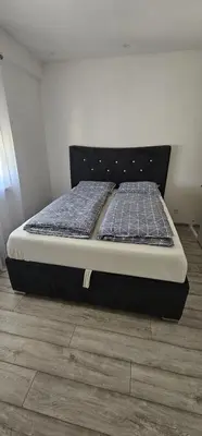 a large bed in a room with a wooden floor at Apartman BINGO Bugojno in Bugojno