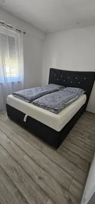 a large bed in a bedroom with a wooden floor at Apartman BINGO Bugojno in Bugojno