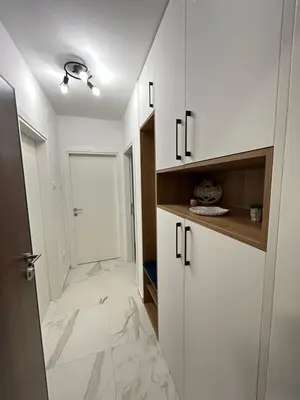 a white kitchen with white cabinets and marble floors at Apartman Maja in Budžak