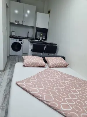 a white bed with two pink pillows in a kitchen at Apartman Novak in Banja Luka