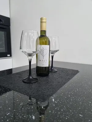 a bottle of wine and two wine glasses on a counter at Apartman Novak in Banja Luka