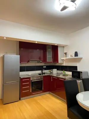 a kitchen with red cabinets and stainless steel appliances at Apartman Sara in Banja Luka