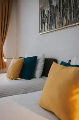 a bed with blue and yellow pillows in a room at Hotel Brcko Gas Doboj in Doboj