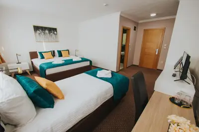 a hotel room with two beds and a desk at Hotel Brcko Gas Doboj in Doboj