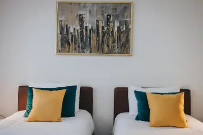 two beds with yellow and blue pillows in a room at Hotel Brcko Gas Doboj in Doboj