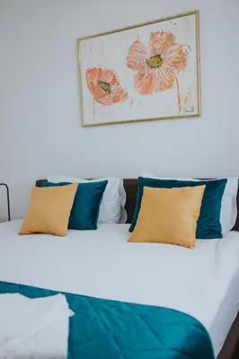 a bed with blue pillows and a picture on the wall at Hotel Brcko Gas Doboj in Doboj