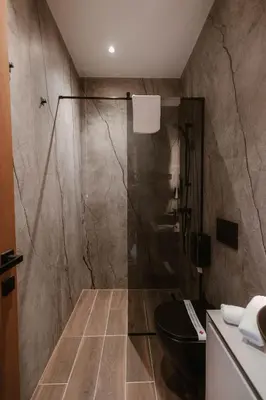 a bathroom with a shower and a black toilet at Tradicija Hotel in Banja Luka
