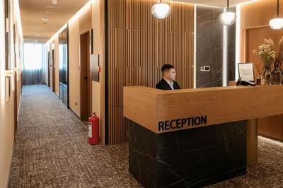 a man sitting at a reception desk in an office at Tradicija Hotel in Banja Luka