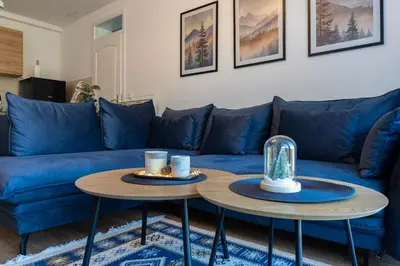a blue couch with two tables in a living room at Apartman Haba Vlašić in Vlasic