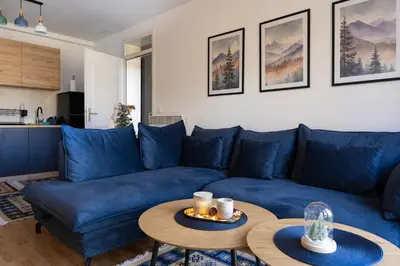 a living room with a blue couch and a table at Apartman Haba Vlašić in Vlasic