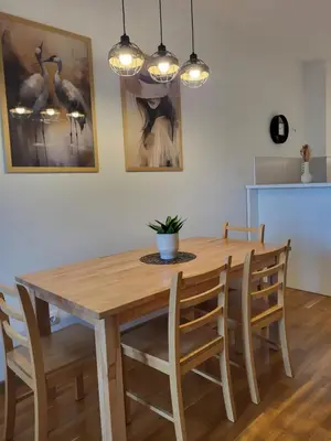 a wooden dining room table with chairs and a table and lights at Green view apartment in Banja Luka