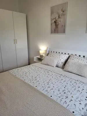 a white bedroom with a large bed and a cabinet at Green view apartment in Banja Luka