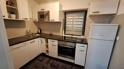 a kitchen with white cabinets and a white refrigerator at Atika in Cazin