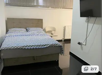 a bedroom with a bed with a blue comforter and a television at EM Apartments in Tuzla