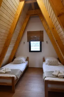 two beds in a attic room with a window at Tasija Relax & Spa in Doboj