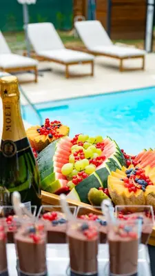 a table with a tray of food next to a swimming pool at Tasija Relax & Spa in Doboj