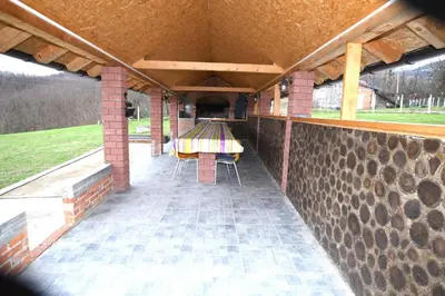a covered patio with a table and chairs on it at Ivanović Vikendica