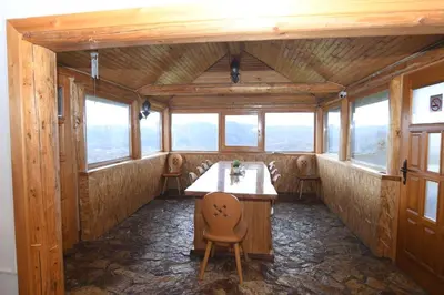 a room with a table and chairs and windows at Ivanović Vikendica