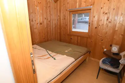 a small bed in a wooden room with a window at Ivanović Vikendica