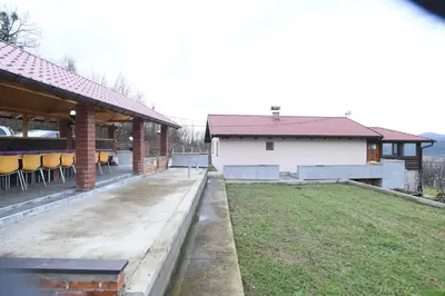 a house with a patio and a yard with chairs at Ivanović Vikendica