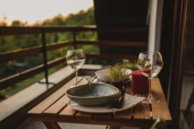 a table with two wine glasses and a bowl on a balcony at Forrest House in Doboj