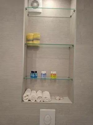a bathroom with a shower with towels on a shelf at Apartman Ditka in Bihać