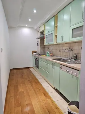 a kitchen with green cabinets and a wooden floor at Ramonda Banja Luka in Banja Luka