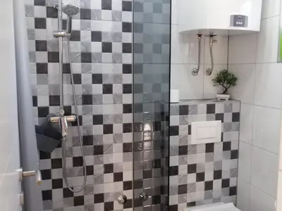 a bathroom with a shower with a checkered tile wall at Kuća za odmor Villa Lana Bihać in Bihać
