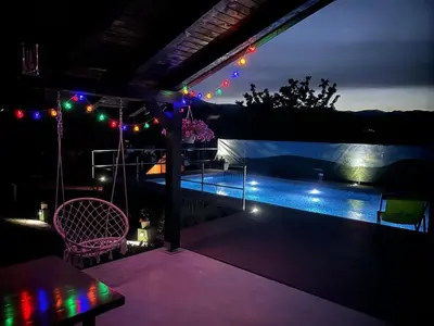 a patio with a pool at night with lights at Kuća za odmor Villa Lana Bihać in Bihać