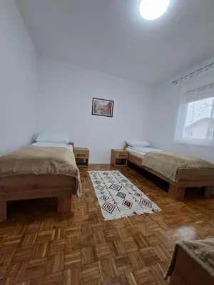 a bedroom with two beds and a rug on the floor at Apartmani E&A Jasmina Okanović in Gradačac
