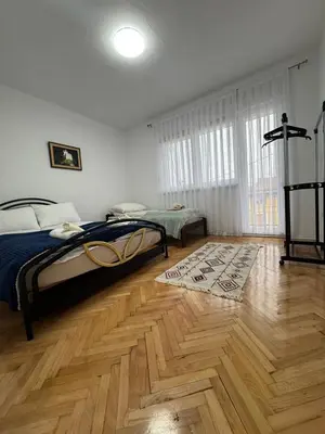 a bedroom with a bed and a wooden floor at Apartmani E&A Jasmina Okanović in Gradačac