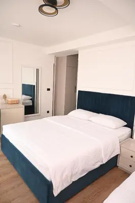 a bedroom with a large bed with a blue headboard at Mas Motel in Bosanska Gradiška