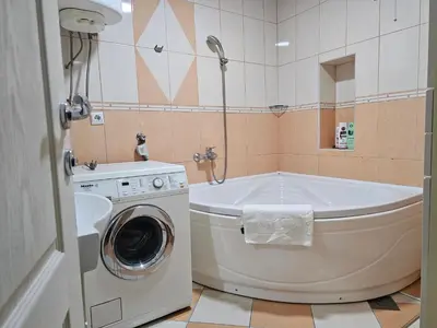 a bathroom with a tub and a washing machine at Ramonda Apartment Banja Luka in Banja Luka