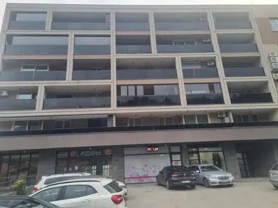 a parking lot in front of a large building at Apartman Sunce in Zenica