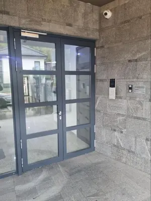 a glass door of a building with a stone wall at Apartman Sunce in Zenica