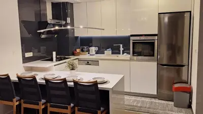 a kitchen with a table with chairs and a refrigerator at Apartman Sunce in Zenica