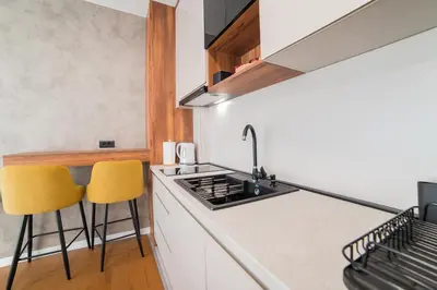 a kitchen with a sink and two yellow chairs at Liberty Studio Tuzla in Tuzla
