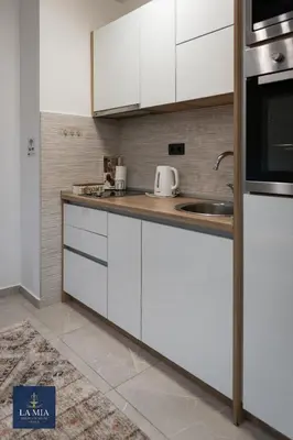 a kitchen with white cabinets and a sink at La Mia Premium Suite in Tuzla