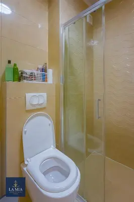 a bathroom with a toilet and a glass shower at La Mia Premium Suite in Tuzla